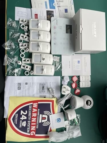 Home security system kit with sensors, control panel, signs, and accessories.